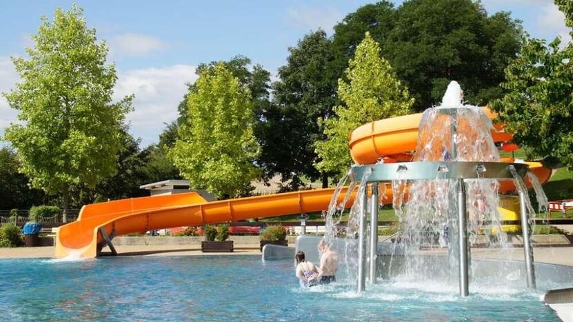 Wasserkaskade und orangefarbene Rutsche im Nichtschimmerbecken