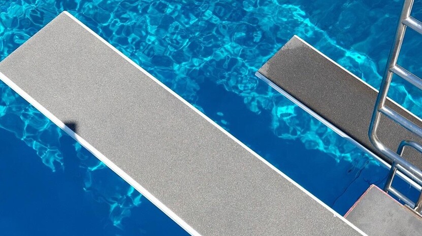 Blick über 2 Sprungbretter in das blau scheinende Wasser des Sprungbeckens