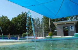 Bunt gekacheltes Planschbecken, darüber blaues Sonnensegel, WC und Wickelraum im Hintergrund