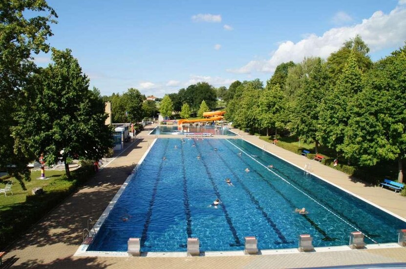 Blick auf das Schwimmerbecken Blick auf das Schwimmerbecken, gesäumt von Baumbestand, im Hintergrund Rutsche im Nichtschwimmerbecken